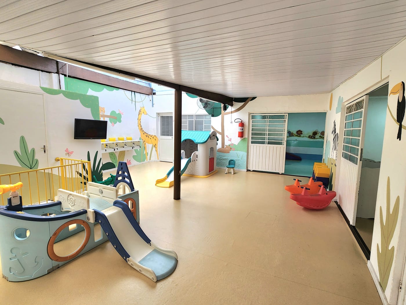 Sala do berçário com escorregador, tapete e decoração colorida