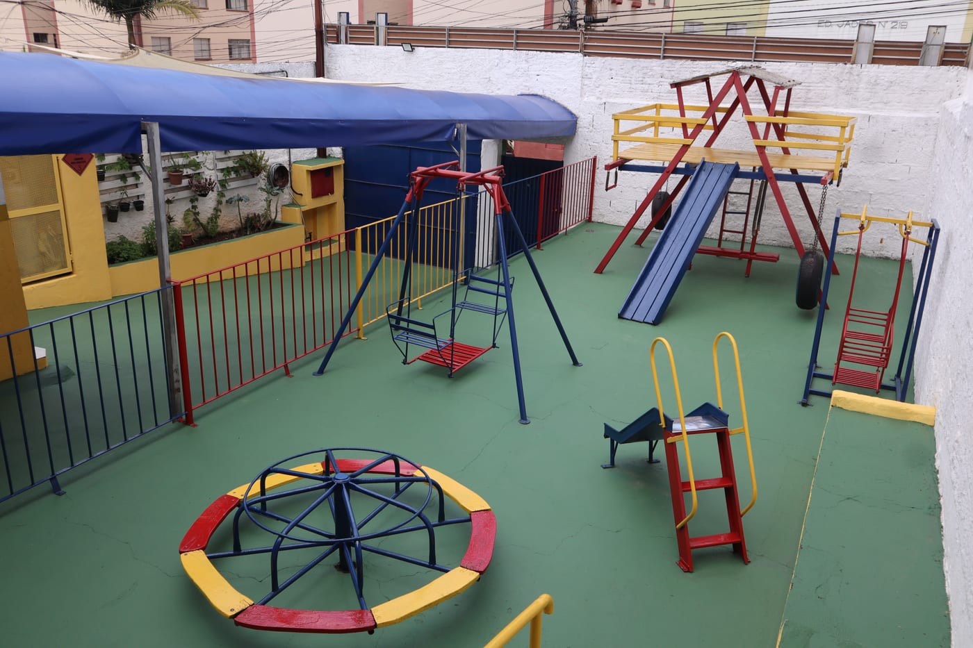 Parque externo da escola, com balanços, escorregadores e brinquedos coloridos