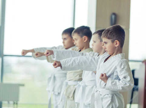 Crianças de kimono praticando um golpe em uma aula de judô