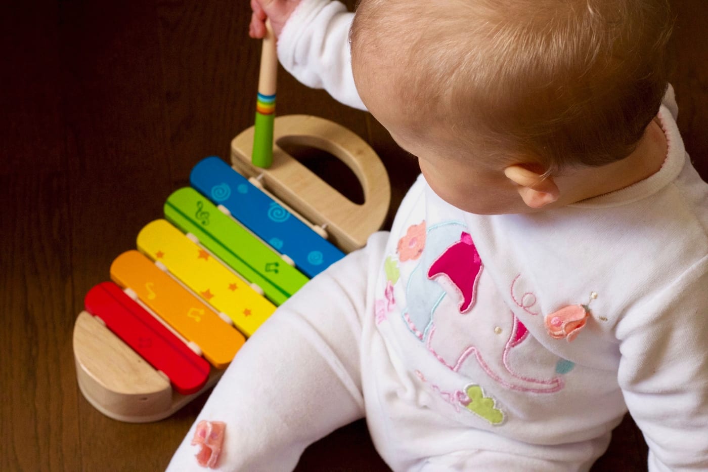 Bebê brincando com um xilofone colorido de madeira