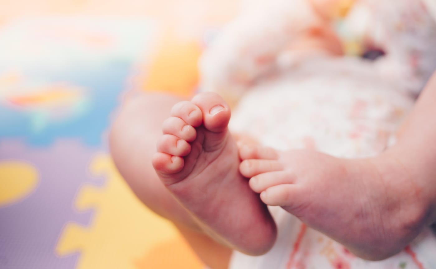 Pezinhos de um bebê sobre um tapete macio e colorido